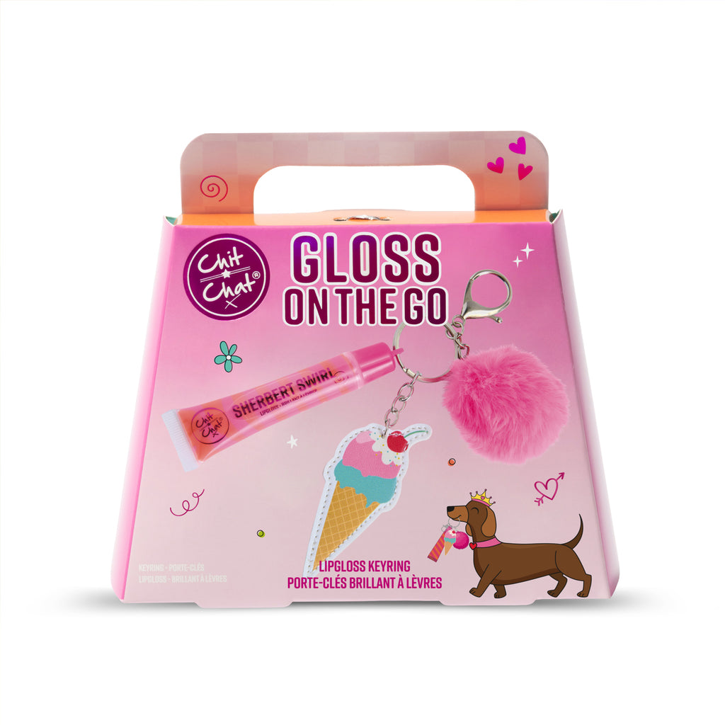 A pink retail box for a lip gloss keyring gift set from Chit Chat, featuring illustrations of a pink lip gloss tube, an ice cream cone charm, and a fluffy pink pom-pom keyring. The box is a two toned pink colour and has a handle cutout.