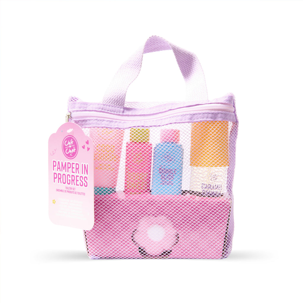 A lavender mesh zippered toiletry bag with four toiletry bottles inside and a pink flower bath bomb, shown on a white background with a pink 'PAMPER IN PROGRESS' tag.
