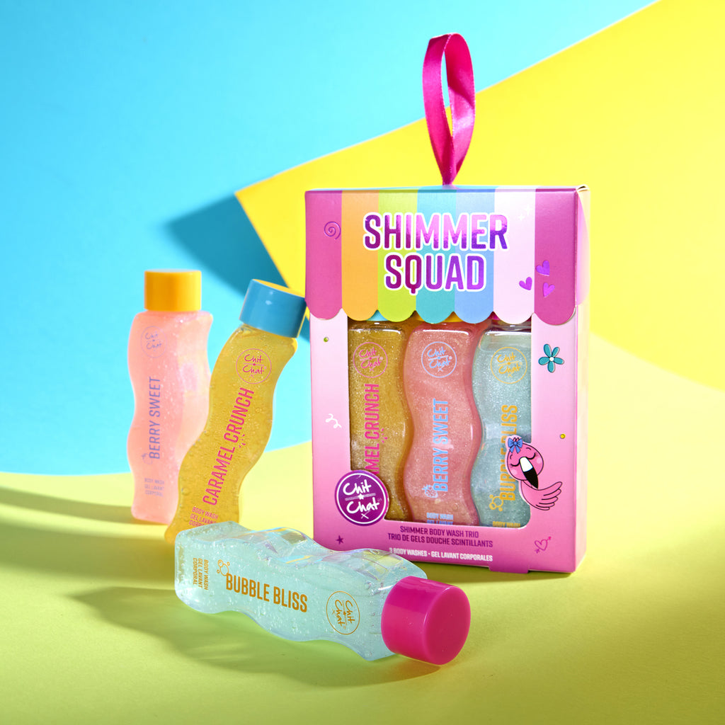 A boxed body wash gift set labelled 'Shimmer Squad' with three body wash bottles inside seen through a cut out window and arranged around the packaging on a bright coloured studio background. 